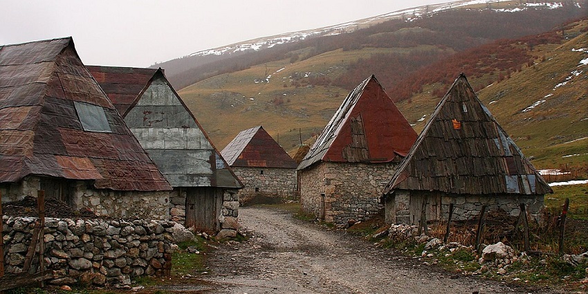 Lukomir highland village with old traditional houses of the village and partial snow on the hills.