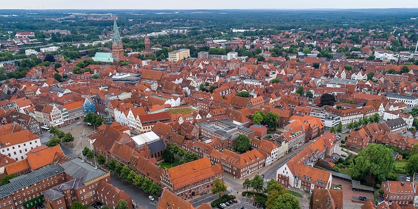 Half-timbered high street lined with wooden buildings and a tall church tower in Lüneburg, one of the top places to visit in Hamburg.
