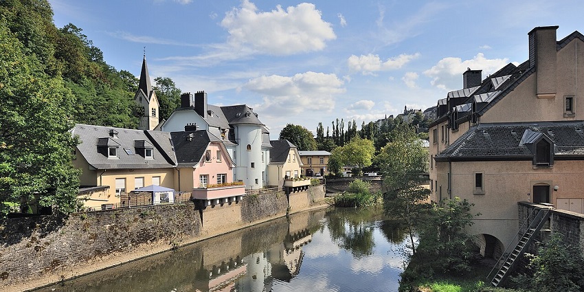 The Lzette River in Pfaffenthal, Luxembourg, with greenery and traditional hillside houses.
