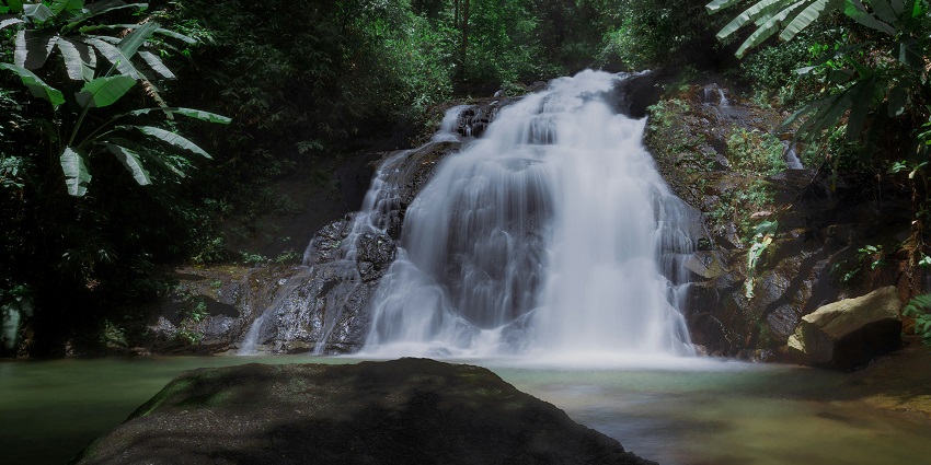 Waterfall surrounded by lush green trees in Mae Kampong village.
