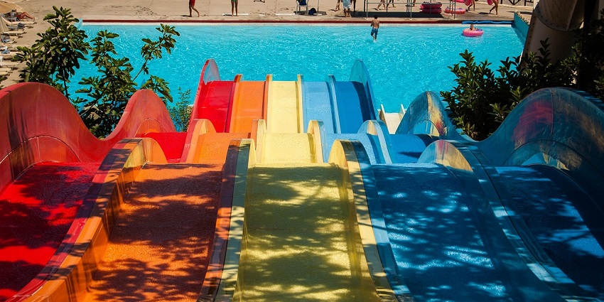 Indoor waterpark with colorful slides, a pool, and people enjoying water rides.