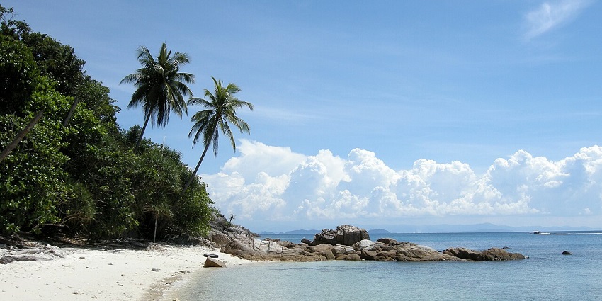 Tropical beach with clear turquoise water and palm trees on Perhentian Kecil, Malaysia.
