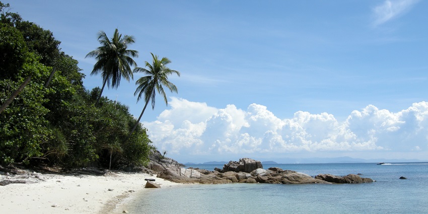 Clear turquoise water of Perhentian Kecil, Malaysia, with white sand and dense greenery, one of the places to visit near Maldives.