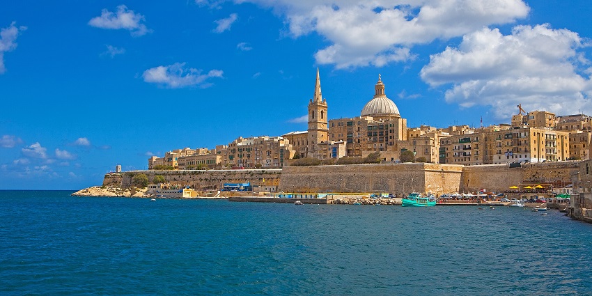 Panoramic view of Malta with calm blue waters and towns stretching along the coastline.
