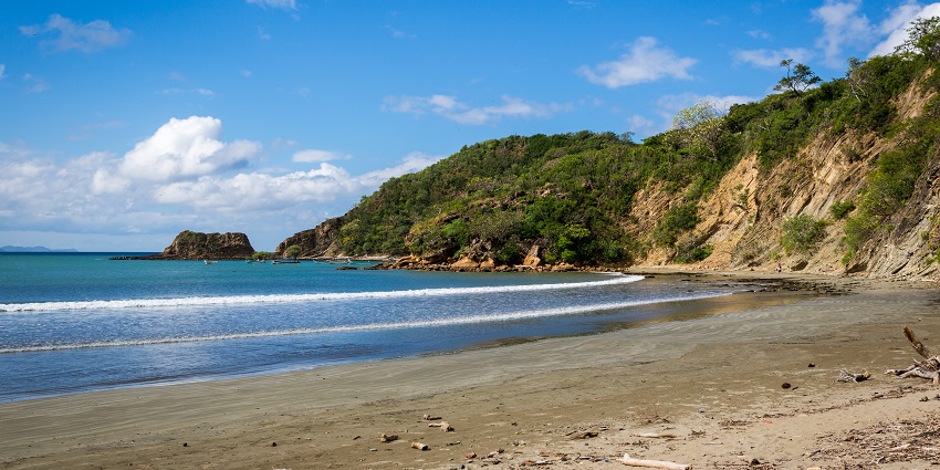 Sandy beach with clear blue water and gentle waves at Managaha Island.