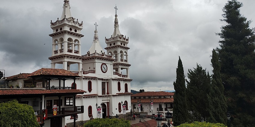 The white twin-towered church in Mazamitla’s main square, framed by tall trees, amongst the best places to visit near Guadalajara.