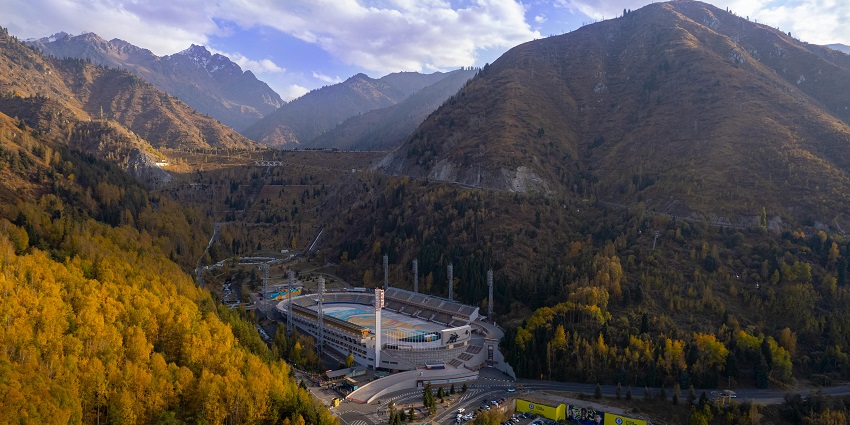 Medeu Skating Rink in Almaty surrounded by green hills and tall pine trees.