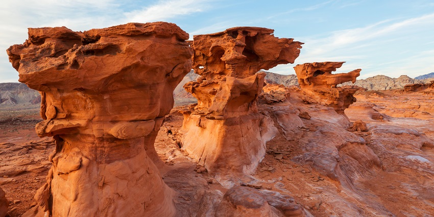 Natural rock formation surrounded by desert landscape and sparse vegetation.