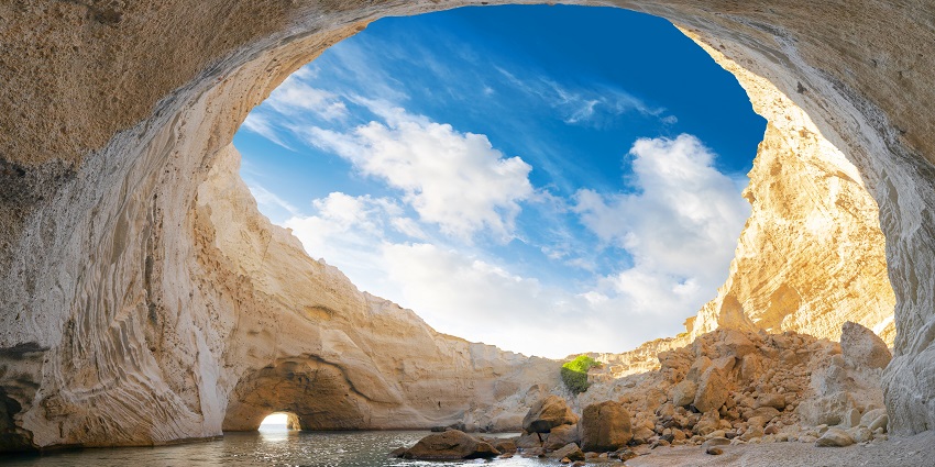 Volcanic open cave of Sykia on Milos island with rocky formations and sea view.