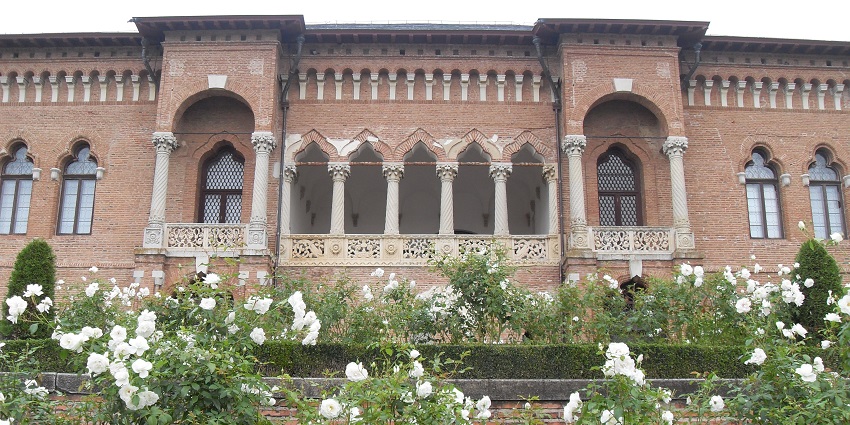 Stylish Brâncovenesc‑style palace surrounded by trimmed gardens with white flowers.