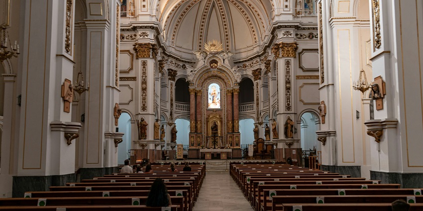 Interior view of Santa María Basilica in Morella showcasing historic architecture and wooden chair stalls.