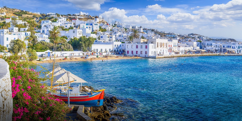 Whitewashed buildings and waterfront view of Mykonos Island under clear skies.