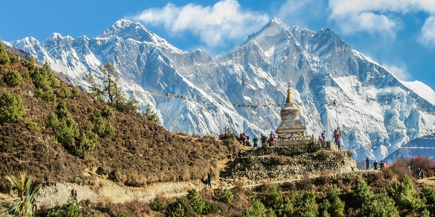 Stupa at Namche Bazaar with mountainous background and clear blue sky.
