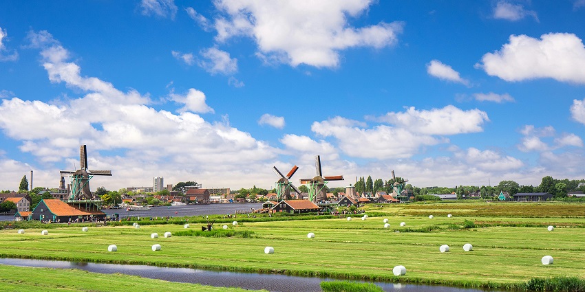 Picturesque green field in Amsterdam with windmills, among the top places to visit near Scotland.