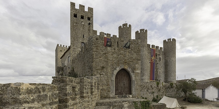 Medieval stone castle with towers and banners near Lisbon, one of the iconic places to visit near Lisbon.