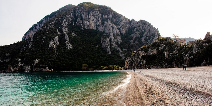 Çıralı Beach with soft sand, turquoise water, and green hills, one of the best places to visit near Antalya.
