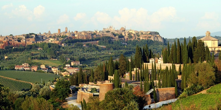 Orvieto with unique long trees, traditional Italian architectural buildings and a distant clock tower.
