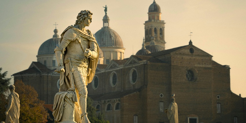 Multiple Detailed white statues in Padova with traditional Italian architecture buildings, one of the top places to visit near Venice.