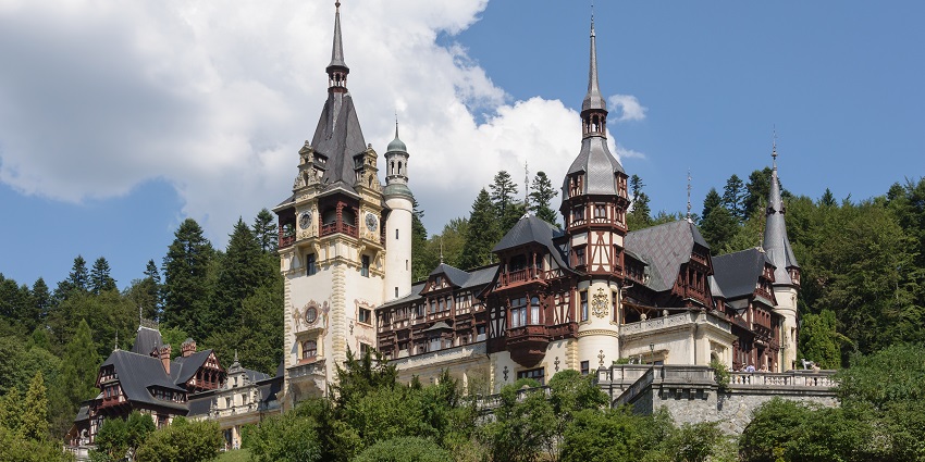 A Neo-Renaissance fairytale-like castle surrounded by greenery under a clear blue sky.