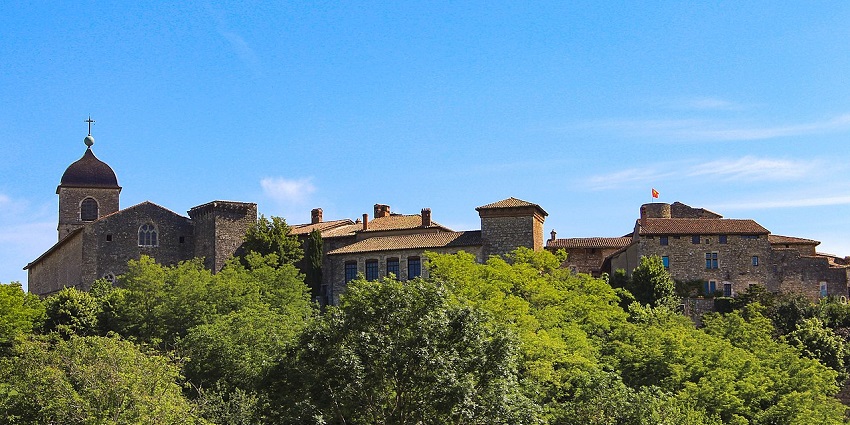 Hilltop stone village with a church tower and lush trees—one of the scenic places to visit near Lyon.