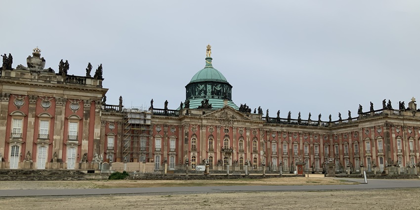 The ornate red and beige New Palace in Potsdam, with statues and a green dome, one of the top places to visit near Berlin.