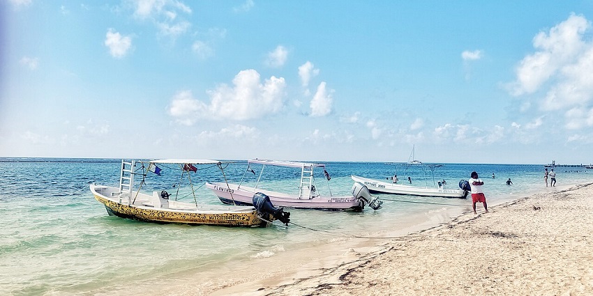 Puerto Morelos beach with soft sand, clear water, boats, near the shore, amongst the top places to visit near Cancun.