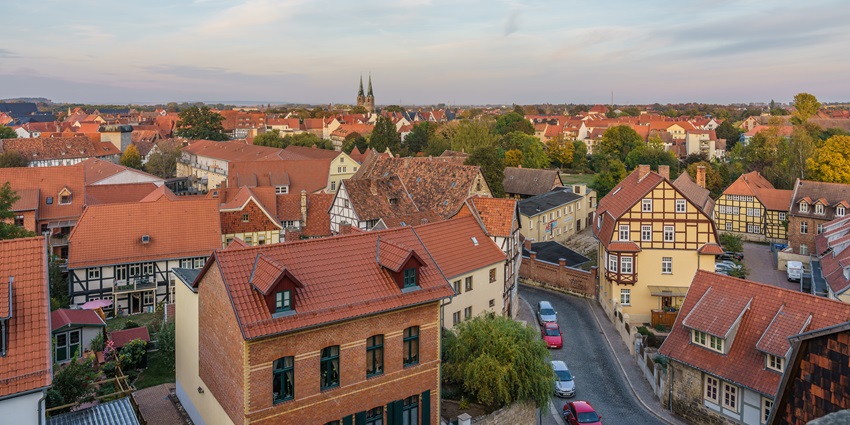 Aerial view of Quedlinburg with red-roofed timber houses and cobblestone streets at sunset.
