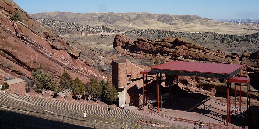 An open-air amphitheatre built into red stone cliffs, with visitors and crisp winter skies.