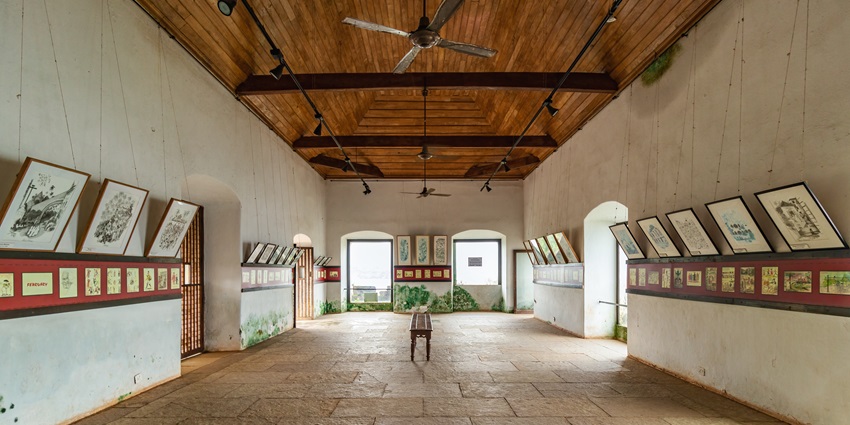 Interior of Reis Magos Fort in Goa with historical paintings displayed on the walls.