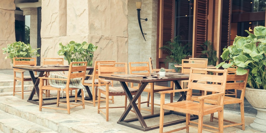 Outdoor café seating with wooden chairs and table under a sunny, relaxed setting.