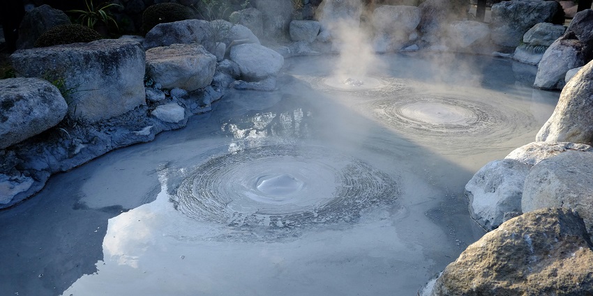 Clear blue water body of hot springs with unique rock formations.