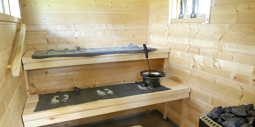 Traditional Finnish sauna with wooden benches and a heated stove, creating a warm setting.