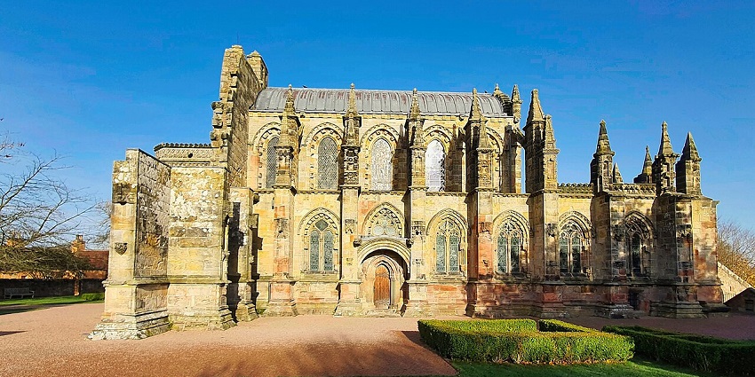 Carved stone work inside Rosslyn Chapel with sunlight streaming through the stained glass.