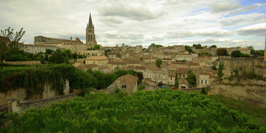 View of Saint-Émilion village with vineyard in foreground and church tower, one of the top places to visit near Bordeaux.