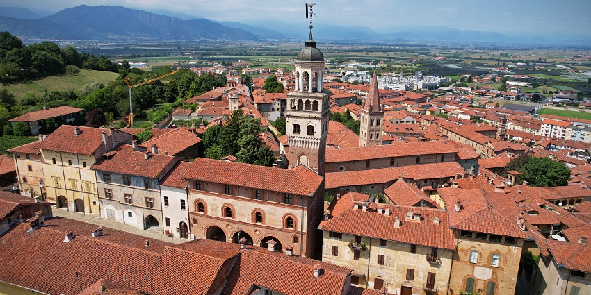 View of Saluzzo with multiple clustered houses set against a scenic hillside backdrop.