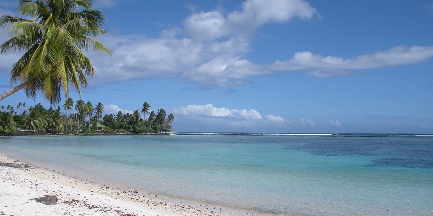Lush green landscape and coastline of Upolu Island, Samoa under a clear sky.
