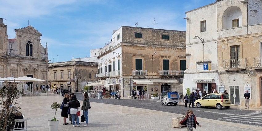 Piazza della Libertà features historic buildings, and people enjoying the day.