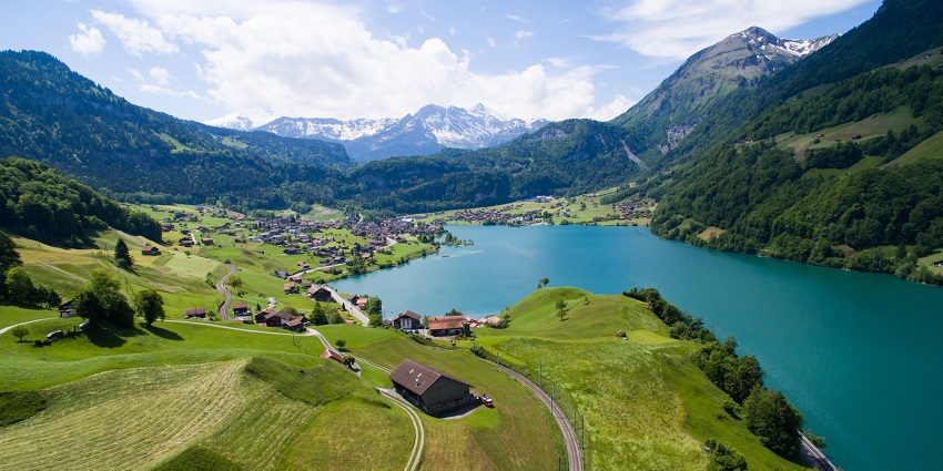 A mesmerising view of the Sarnersee lake with snow-covered mountains and multiple distant houses near the lake.