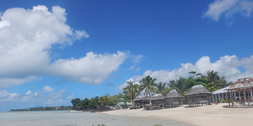 A pristine beach with turquoise waters and tropical huts along the coast of the Samoa Islands.
