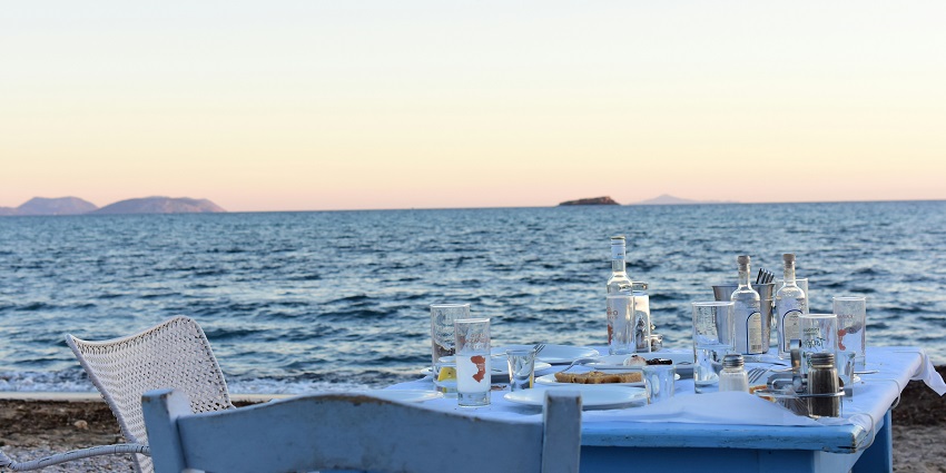Rooftop dining setup with tables overlooking the beach under the evening sky.
