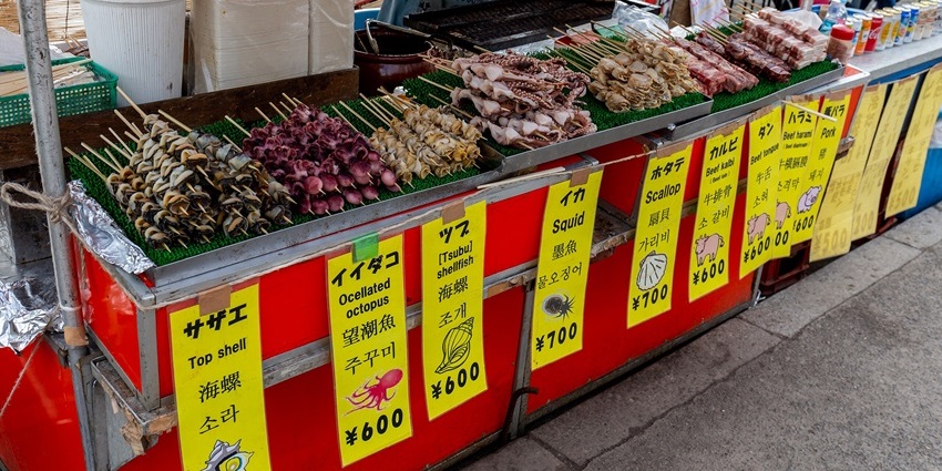Visit colourful seafood stalls at Ueno Park with skewered shellfish, squid, and handwritten signs, one of the things to do in Maiori.