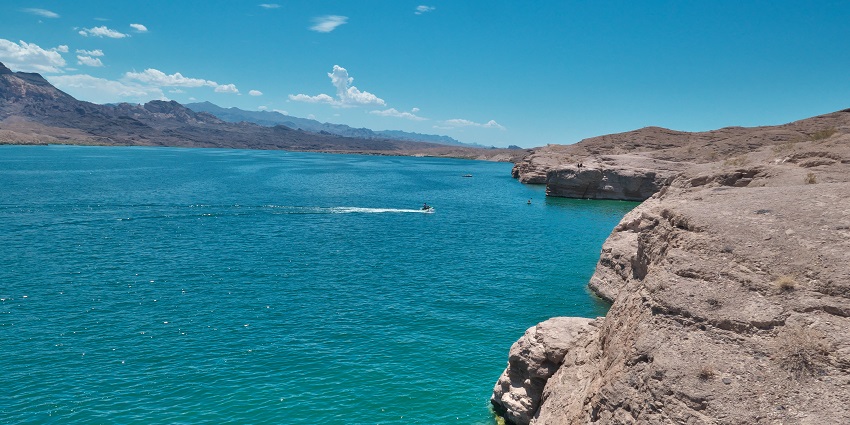 Rocky shoreline with calm water and desert hills near Searchlight, Nevada.