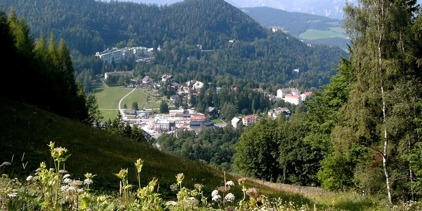 Semmering from above in Austria with distant buildings, green trees, and mountains.