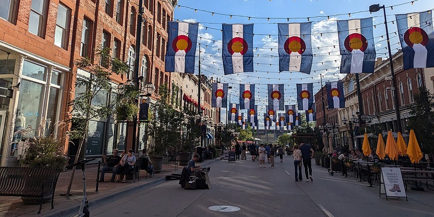 Larimer Square in Denver with brick buildings, Colorado flags, and string lights overhead, amongst the best things to do in Denver Colorado in Winter.