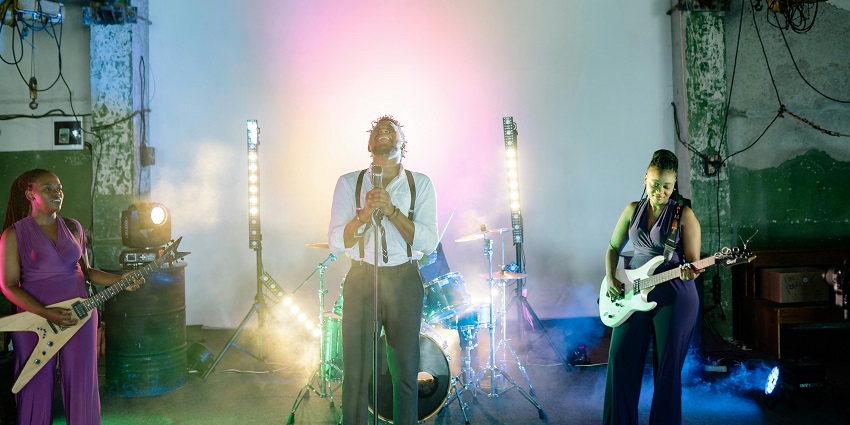 A music band performing on stage with instruments under bright stage lighting.