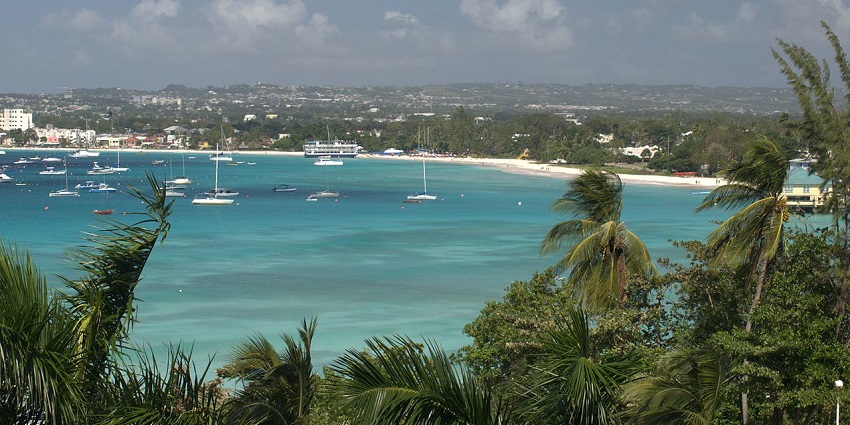 Carlisle Bay from a distance with a distant sandy shoreline, multiple boats in the bay and buildings.