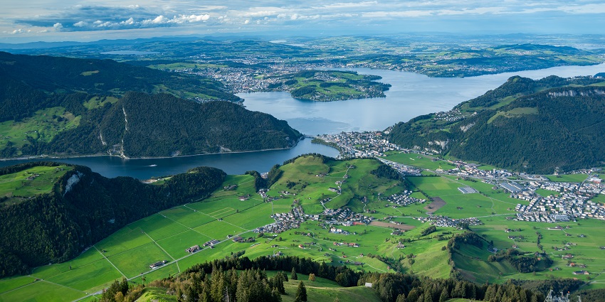 Stanserhorn mountain with green slopes, distant lake, and alpine scenery.