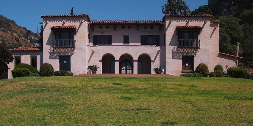 The Wattles Mansion with arches, balconies, and a lush green lawn.
