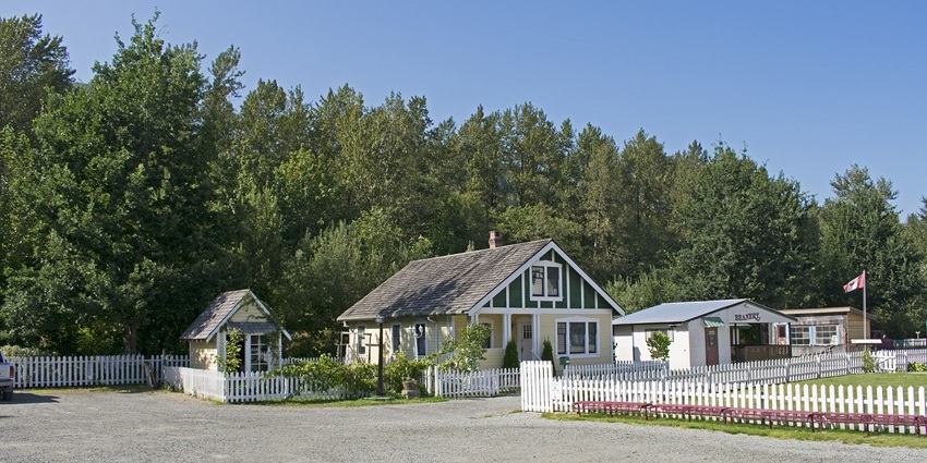 Historic-style houses with white fences at West Coast Railway Heritage Park, one of the best things to see in Lynnwood.