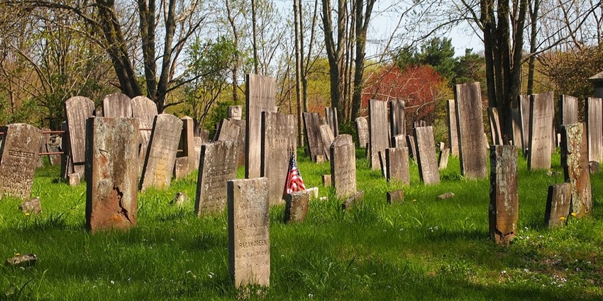 Old cemetery with weathered tombstones scattered across grass, one of the best things to do in Norwich CT.